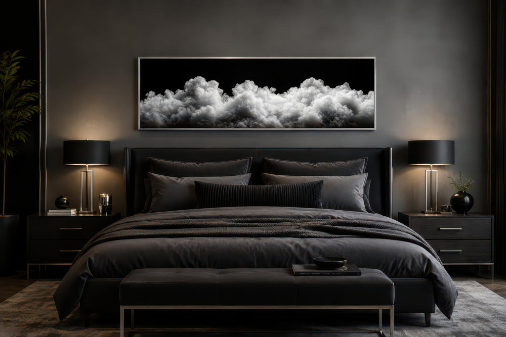 Black and white clouds long horizontal framed canvas wall art hanging above a bed in a dark bedroom.