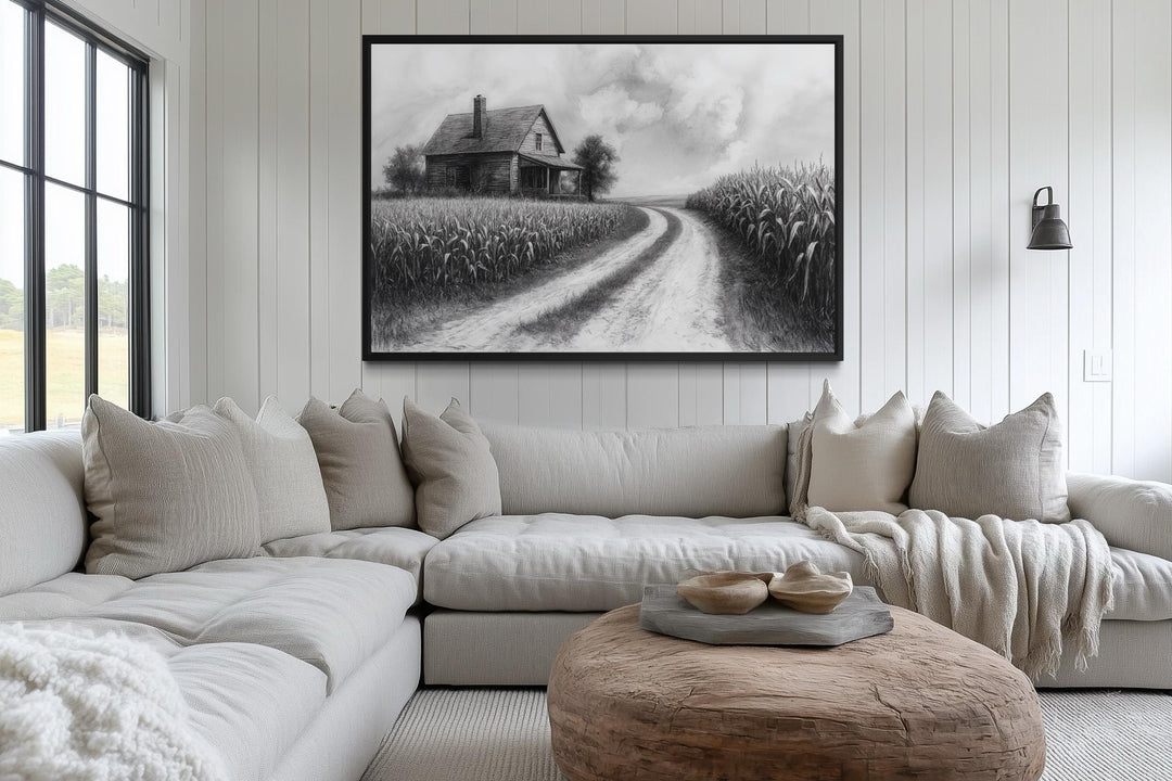 Black and white farmhouse wall art featuring a cornfield and country road above a neutral sofa.