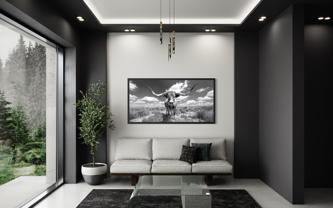 Black and white longhorn photography style framed canvas wall art centered above a modern sofa.