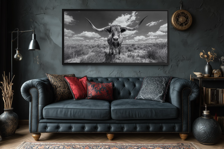 Black and white longhorn photography style framed canvas wall art above a dark tufted sofa.