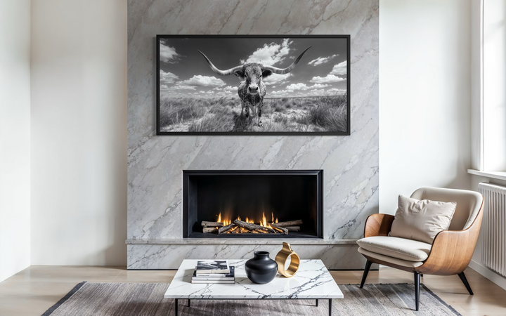 Black and white longhorn photography style framed canvas wall art displayed above a fireplace.
