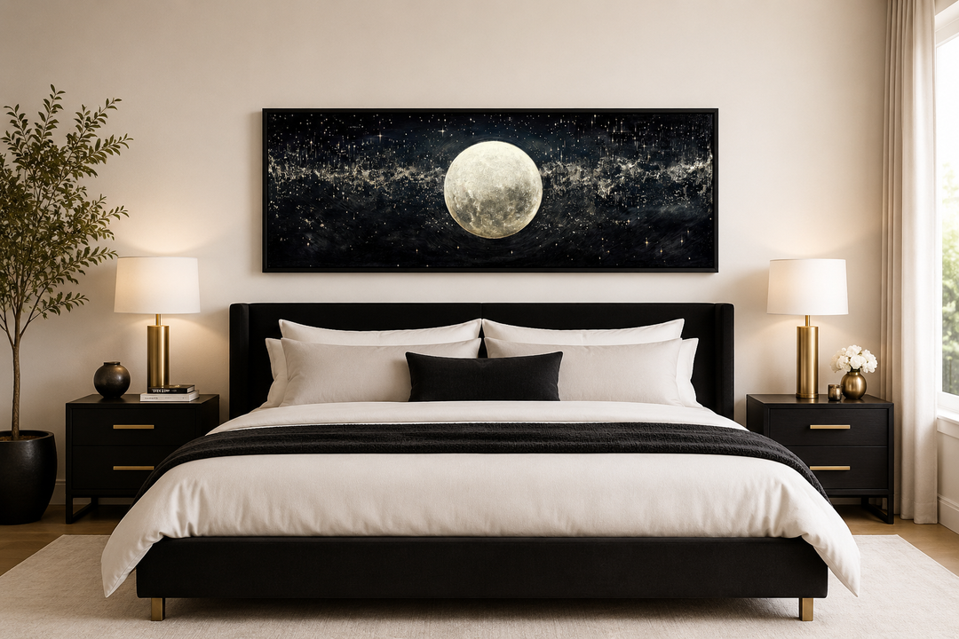 Horizontal black and white canvas print of a full moon in a starry sky hanging above a bed.