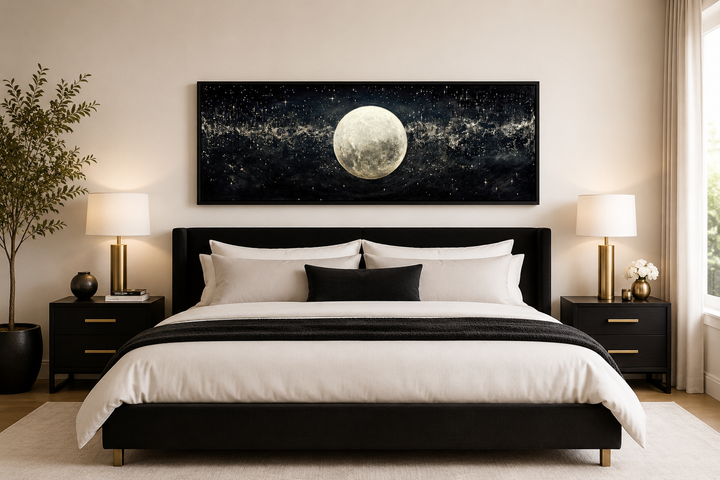 Horizontal black and white canvas print of a full moon in a starry sky hanging above a bed.