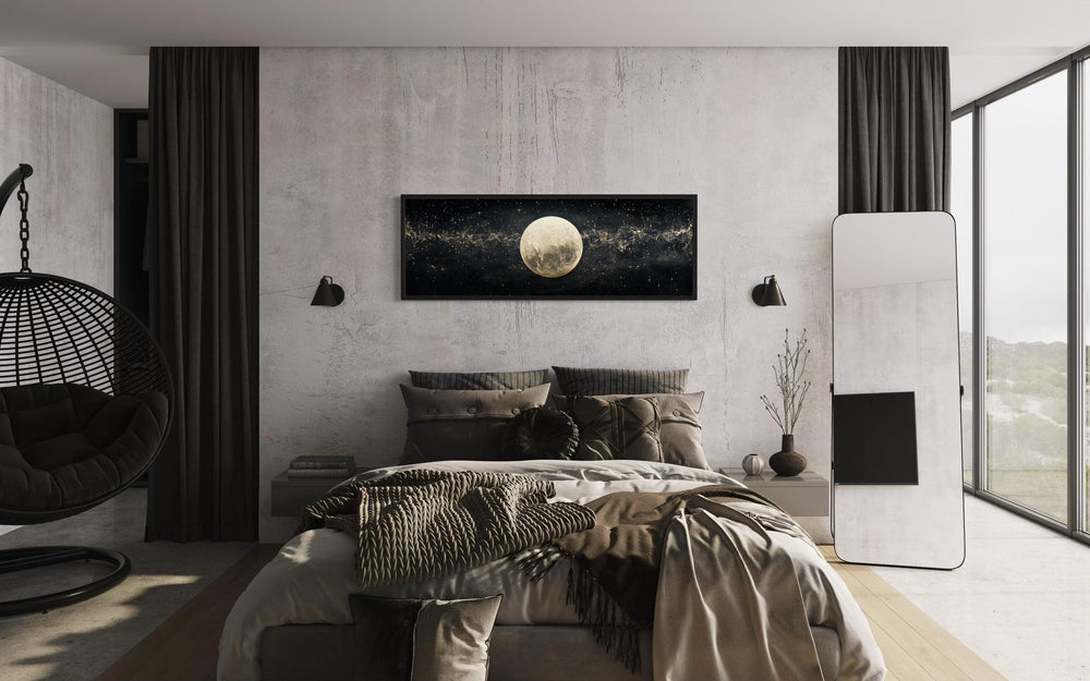 Horizontal black and white wall art of a full moon in a starry sky hanging above a modern bed.