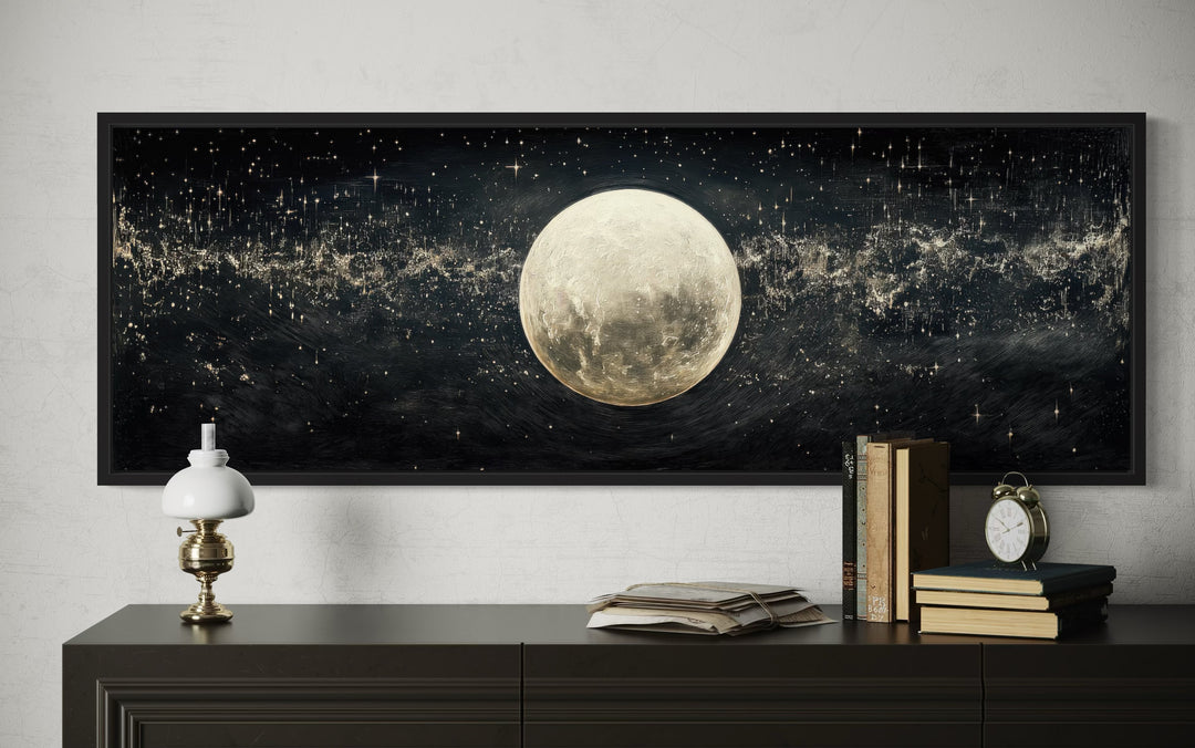 Horizontal black and white canvas art of a full moon in a starry sky above a dark wood dresser.