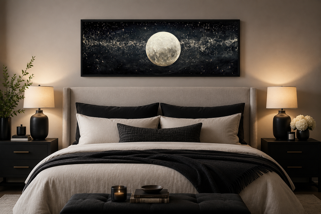 Horizontal black and white canvas art of a full moon in a starry sky hanging above a bed.