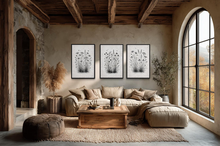 Set of three black and white wildflower canvas prints in a rustic farmhouse living room.
