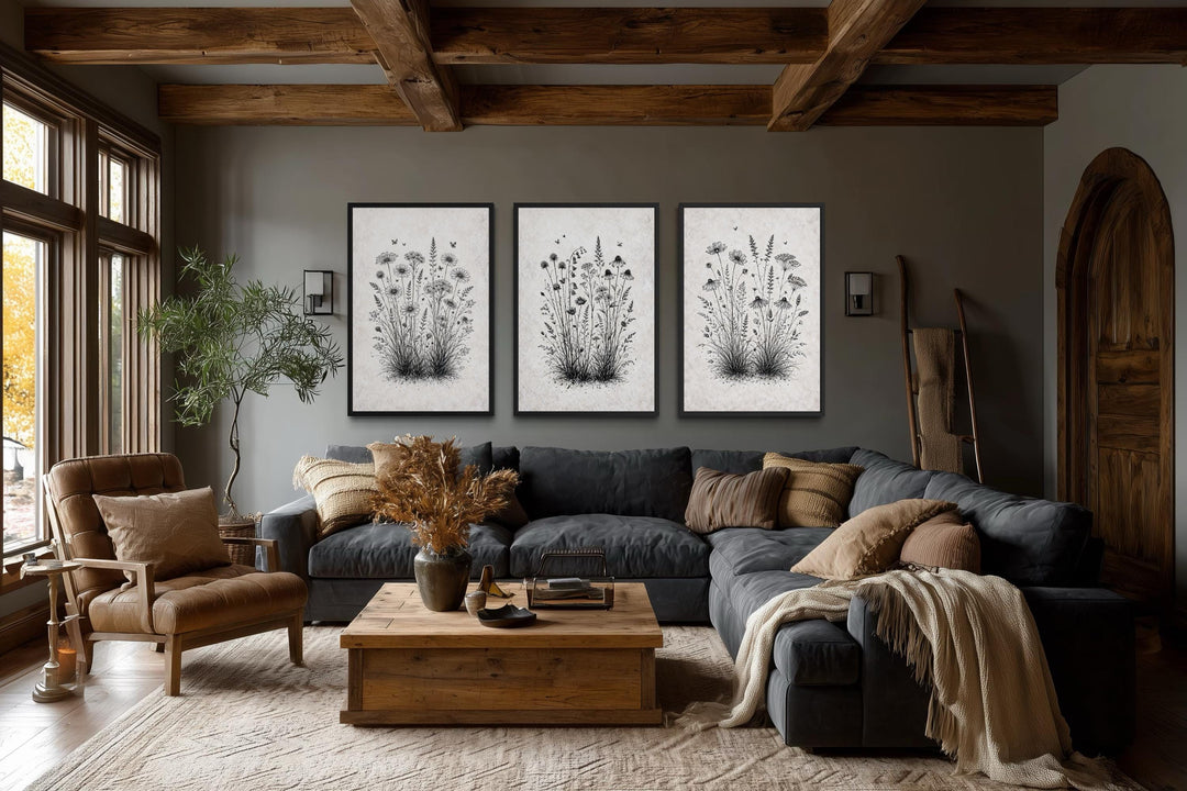 Set of three black and white wildflower canvas prints in a rustic farmhouse living room.