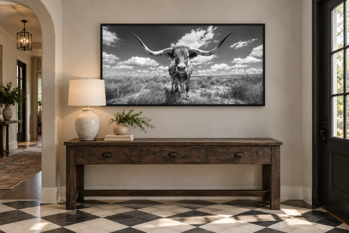 Black and white longhorn photography style framed canvas wall art above a wooden console table.
