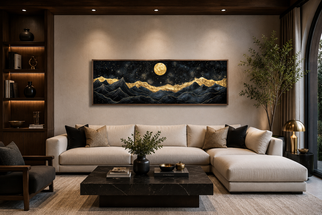 Wide canvas print of black and gold mountains under a full moon in a modern living room.