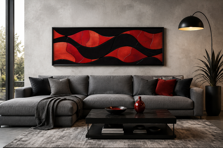 Horizontal framed canvas wall art with red and black abstract waves above a grey sectional sofa.