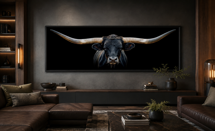 Panoramic framed canvas wall art of a black Texas longhorn steer hanging above a living room couch.