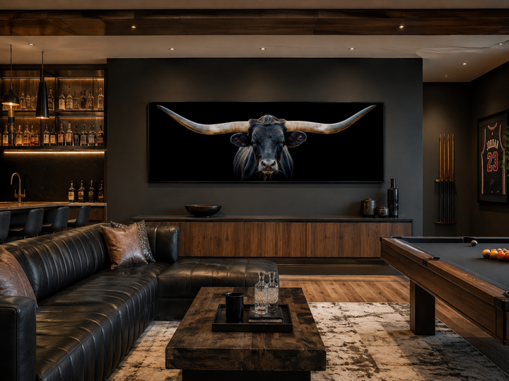 Panoramic framed canvas wall art of a black Texas longhorn steer above a black leather couch.