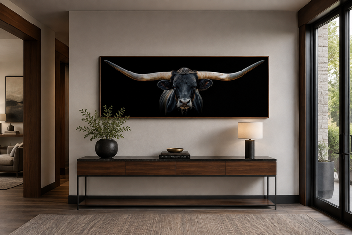 Panoramic framed canvas wall art of a black Texas longhorn steer above a wooden console table.