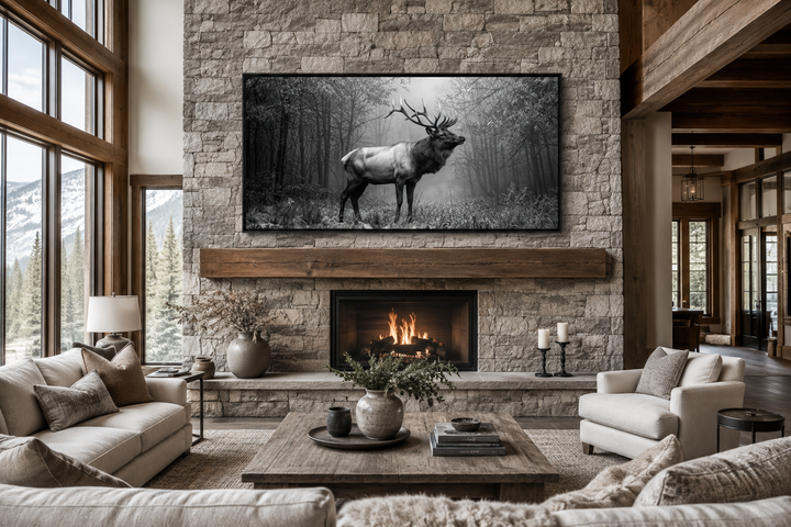 Black and white elk stag in the forest framed canvas wall art above a stone fireplace.