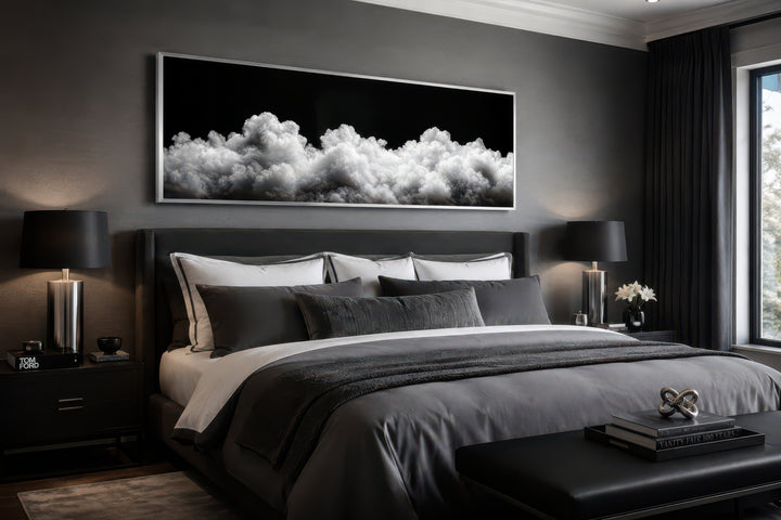 Black and white clouds long horizontal framed canvas wall art hanging above a bed in a bedroom.