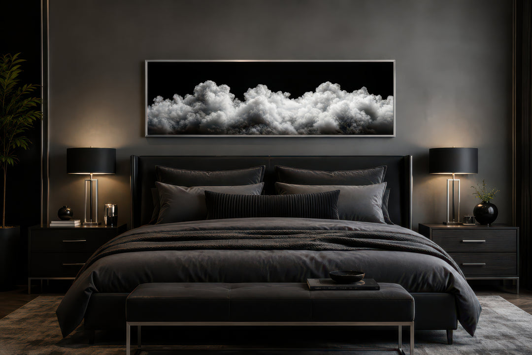 Black and white clouds long horizontal framed canvas wall art hanging above a bed in a dark bedroom.