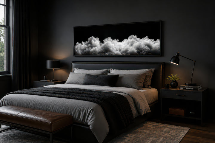 Black and white clouds long horizontal framed canvas wall art above a bed in a dark bedroom.