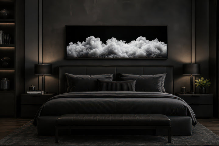 Black and white clouds long horizontal framed canvas wall art hanging above a bed in a dark bedroom.