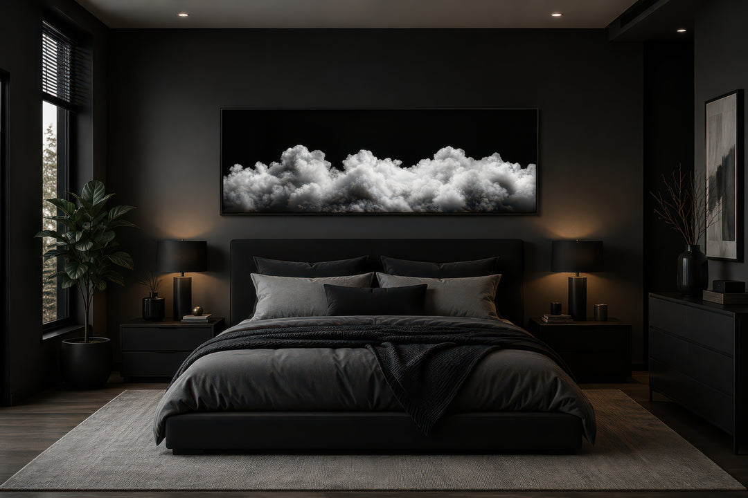 Black and white clouds long horizontal framed canvas wall art hanging above a bed in a dark bedroom.