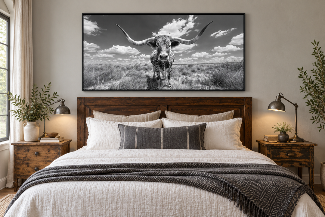 Black and white framed longhorn photography canvas art hanging above a wooden bed in a bedroom.
