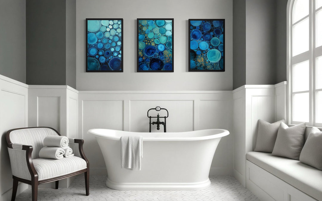 Set of 3 blue aqua and navy bubble abstract canvas prints hanging above a white bathtub.