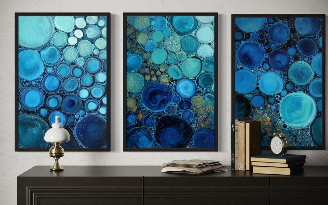 Set of 3 blue aqua and navy bubble abstract canvas prints displayed above a dark console table.