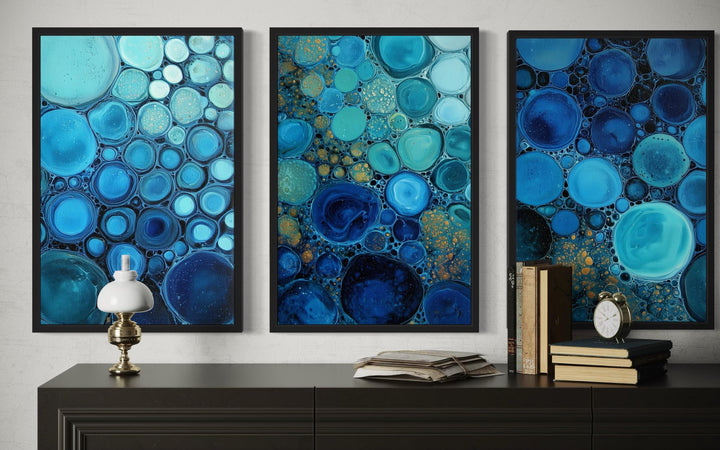 Set of 3 blue aqua and navy bubble abstract canvas prints displayed above a dark console table.