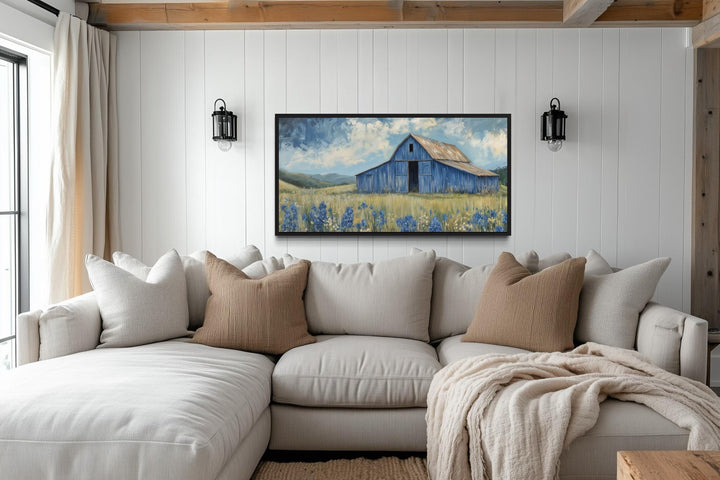 Blue Barn and Bluebonnets rustic framed canvas wall decor hanging above a neutral sectional sofa.