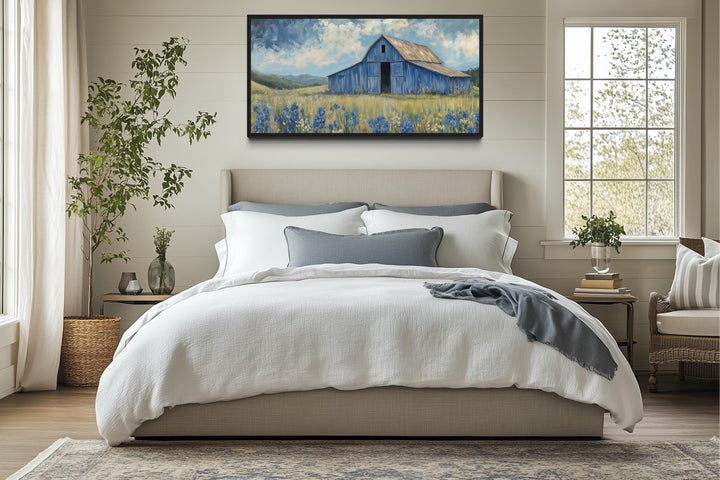 Blue Barn and Bluebonnets rustic framed canvas wall decor hanging above a bed in a farmhouse room.