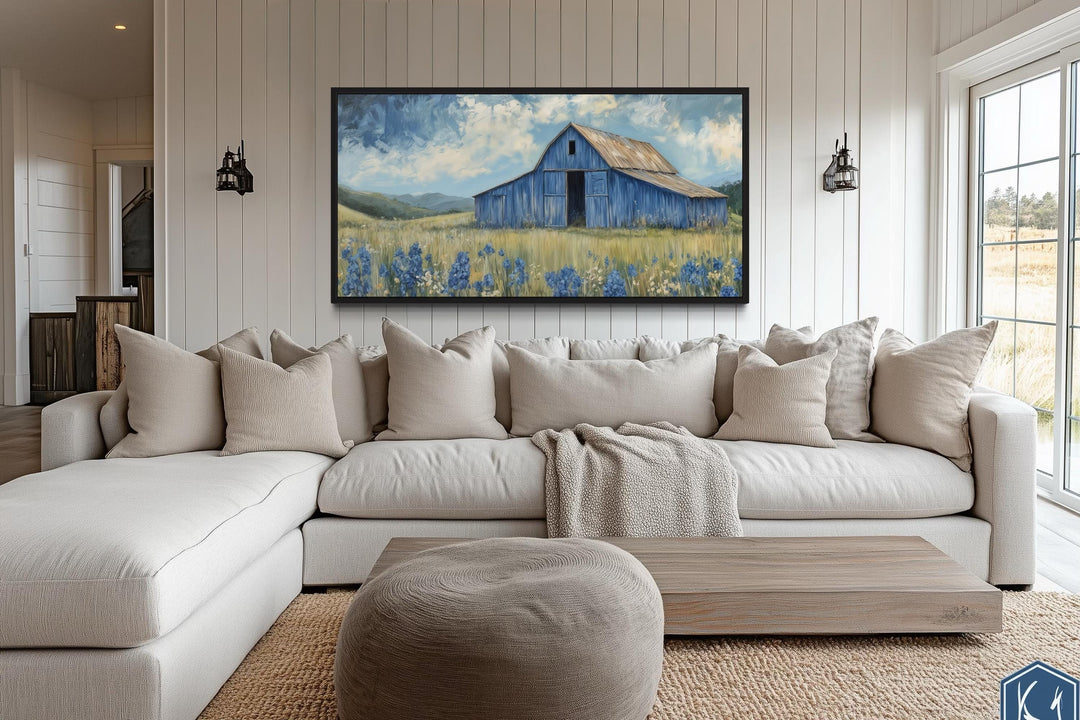 Blue barn and bluebonnets rustic framed canvas wall decor above a neutral sectional sofa.