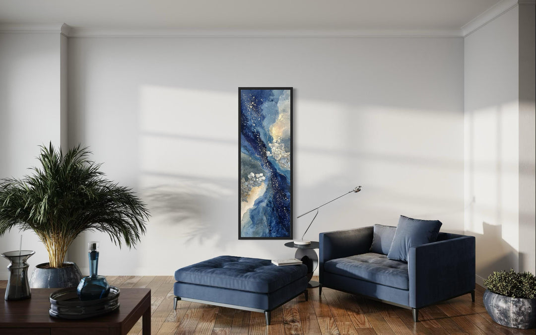 Tall narrow abstract canvas print with navy, beige, and gold tones in a modern living room setting.