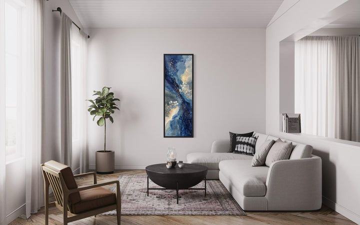 Tall narrow abstract canvas print with navy, beige, and gold tones in a modern living room.