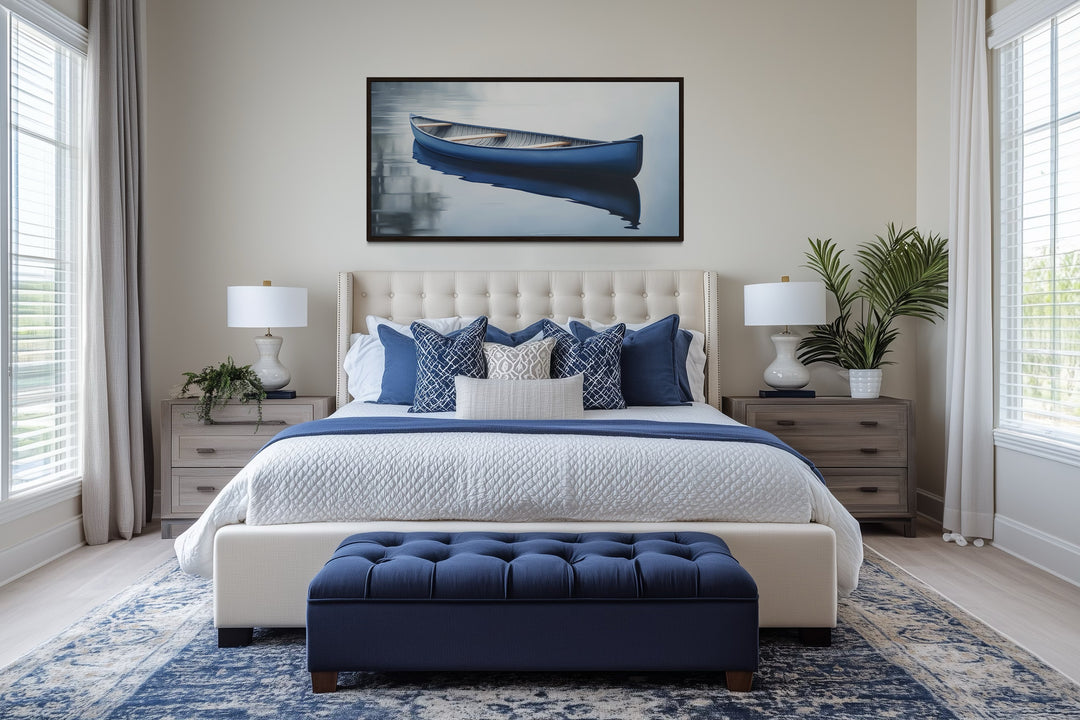 Framed canvas wall art of a blue canoe on a calm lake hanging above a bed in a modern bedroom.