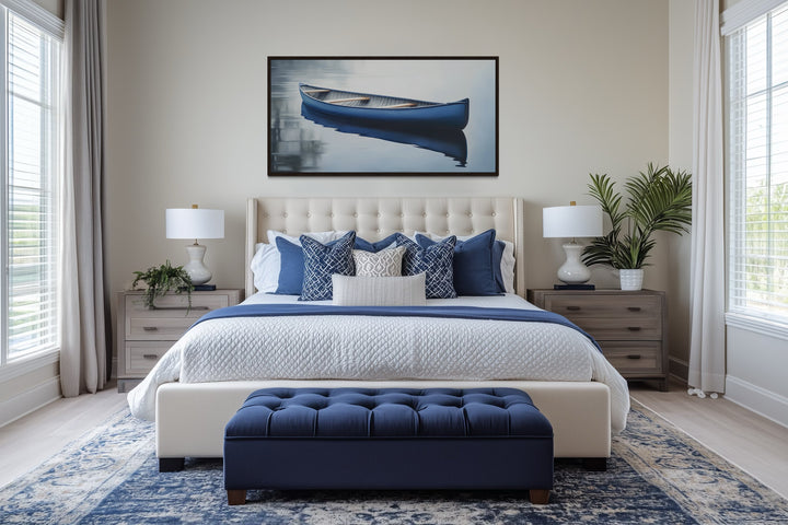 Framed canvas wall art of a blue canoe on a calm lake hanging above a bed in a modern bedroom.