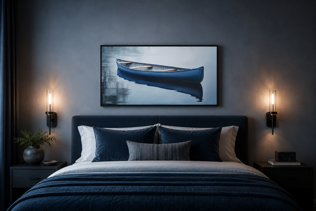 Framed canvas wall art of a blue canoe on a calm lake hanging above a modern bed.