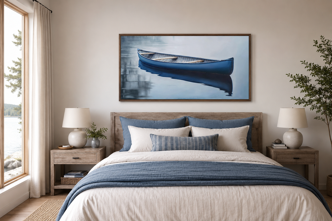 Framed canvas wall art of a blue canoe on a serene lake, hanging above a bed in a bedroom.