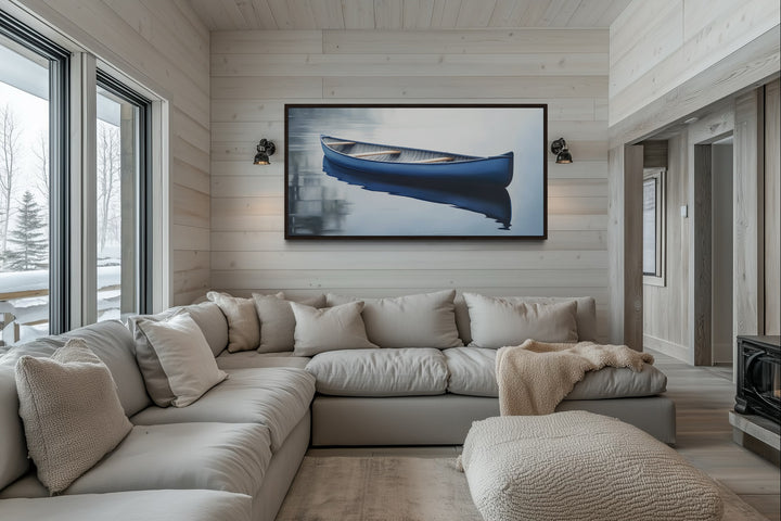 Framed canvas wall art of a blue canoe on a calm lake, hanging above a neutral sectional sofa.