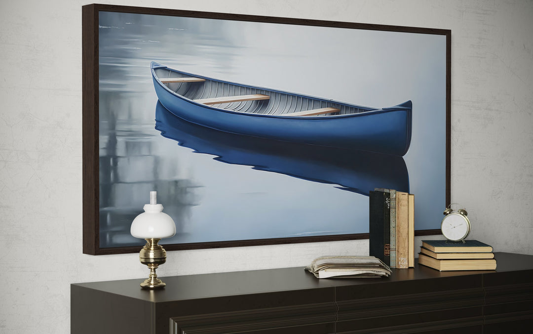 Framed canvas wall art of a blue canoe on a calm lake, displayed above a dark wood dresser.