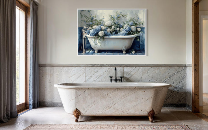 Blue and white hydrangea flowers in a vintage clawfoot tub canvas print hanging in a bathroom.