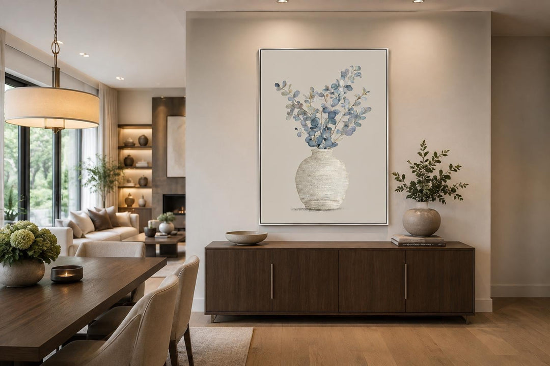 Blue floral still life wall art with eucalyptus branches in a textured vase over a dining sideboard.