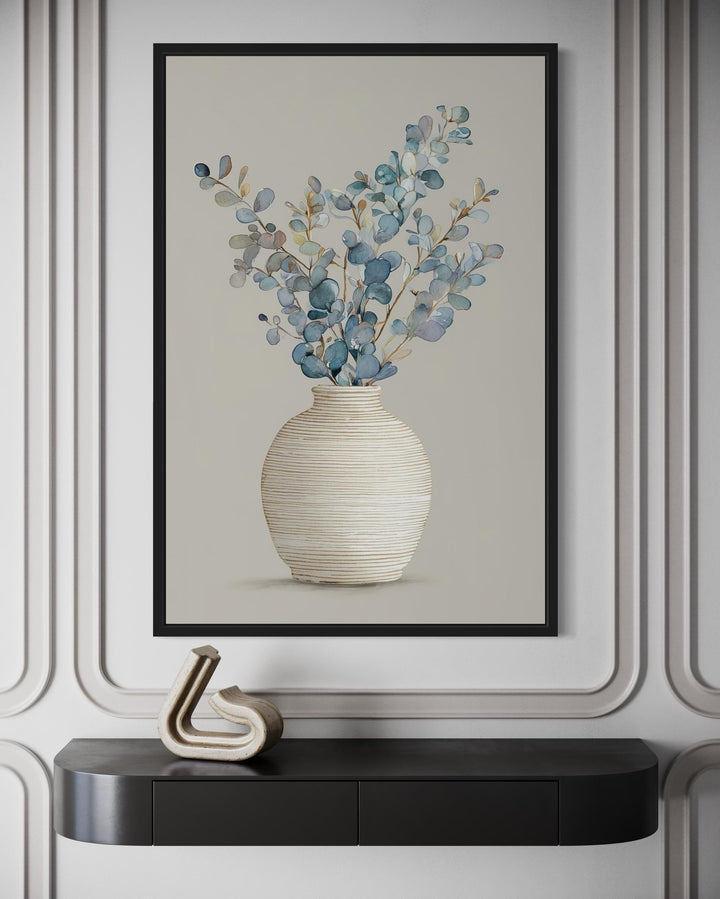 Blue floral still life wall art featuring eucalyptus branches in a textured vase on a cream wall.