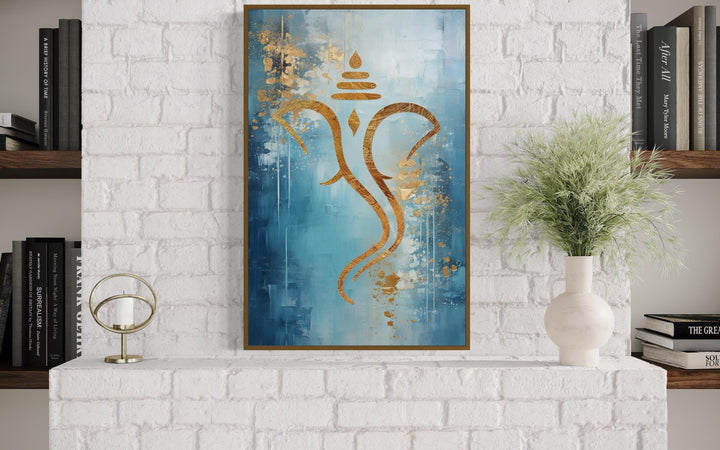 Blue and gold minimalist Lord Ganesha framed canvas wall art displayed above a white brick fireplace
