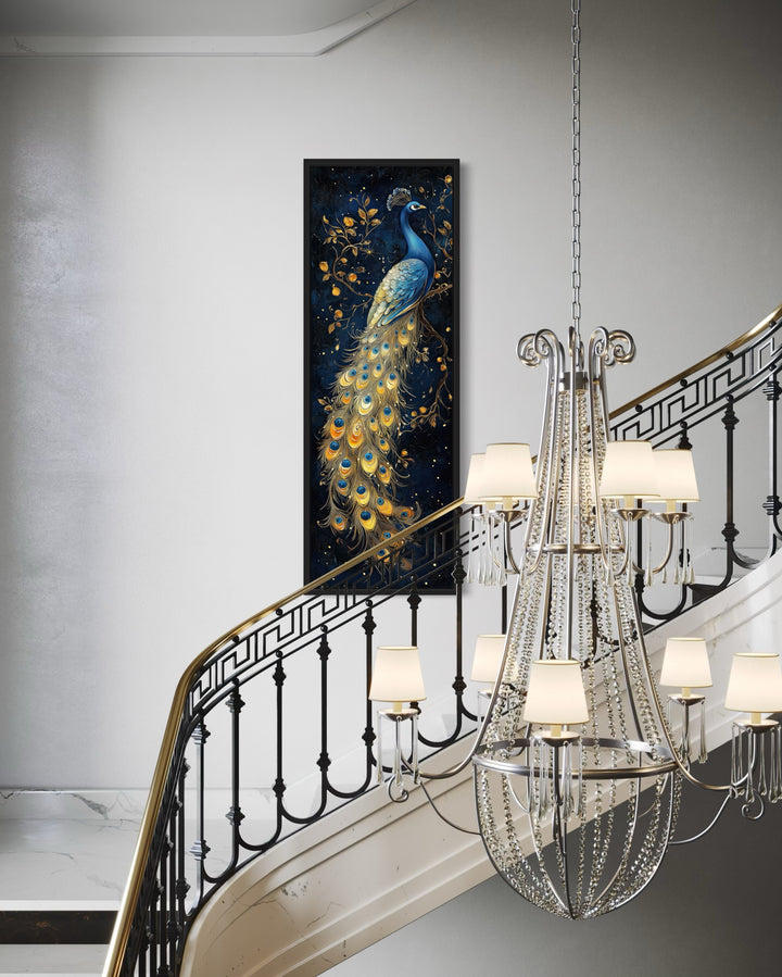 Tall narrow framed canvas wall art featuring a blue and gold peacock on a staircase wall.