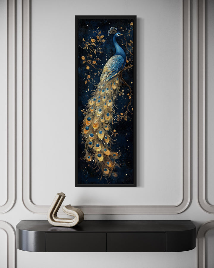 Tall narrow vertical framed canvas wall art featuring a blue and gold peacock on a navy background.