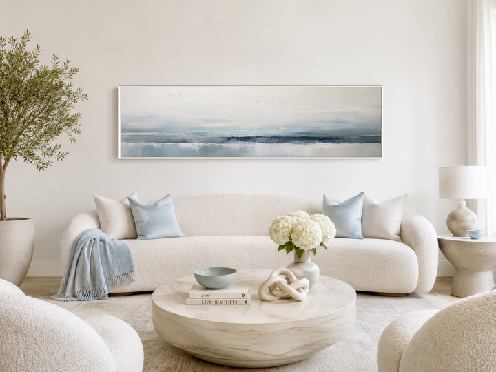 Blue gray calm coastal framed canvas wall art hanging above a white sofa in a modern living room.