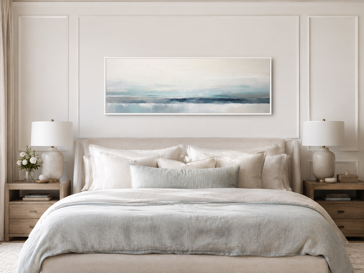 Blue gray calm coastal framed canvas wall art hanging above a bed in a modern bedroom.
