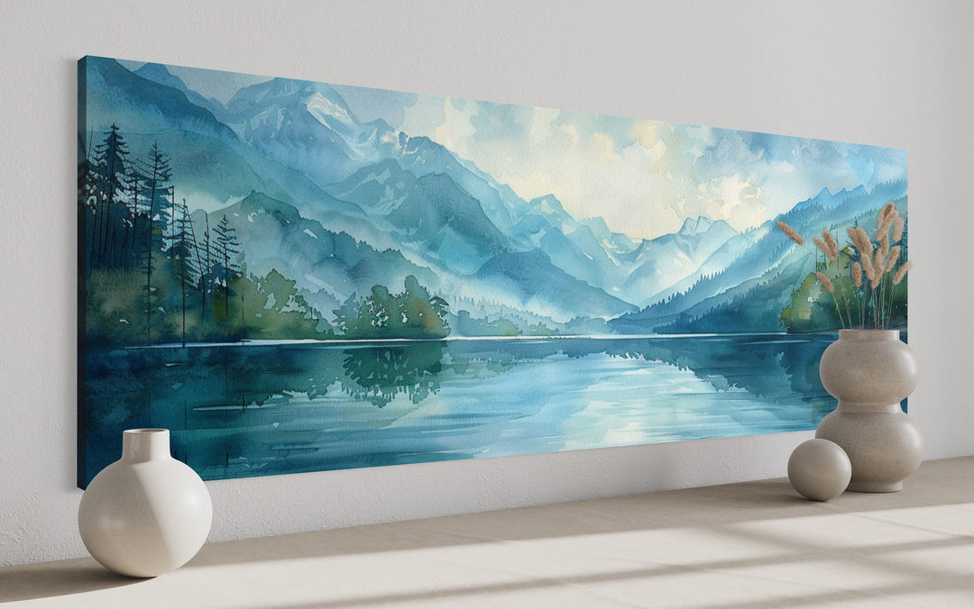 Panoramic watercolor canvas of a blue mountain lake with green pines and misty peaks.