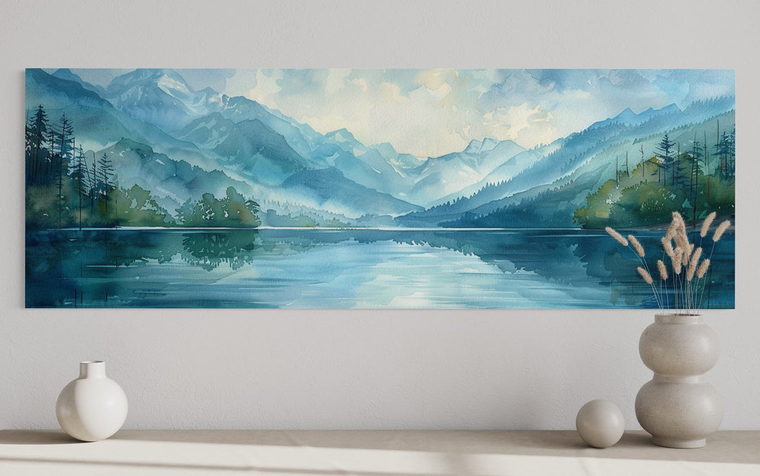 Panoramic watercolor wall art of a misty blue mountain lake with green pine tree reflections.