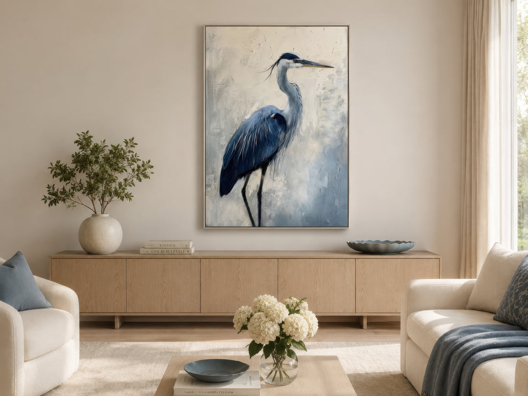 Blue heron abstract painting in a thin silver frame hanging above a light wood sideboard.